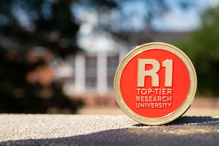 Gold and red coin that says "R1 Top-Tier Research University"